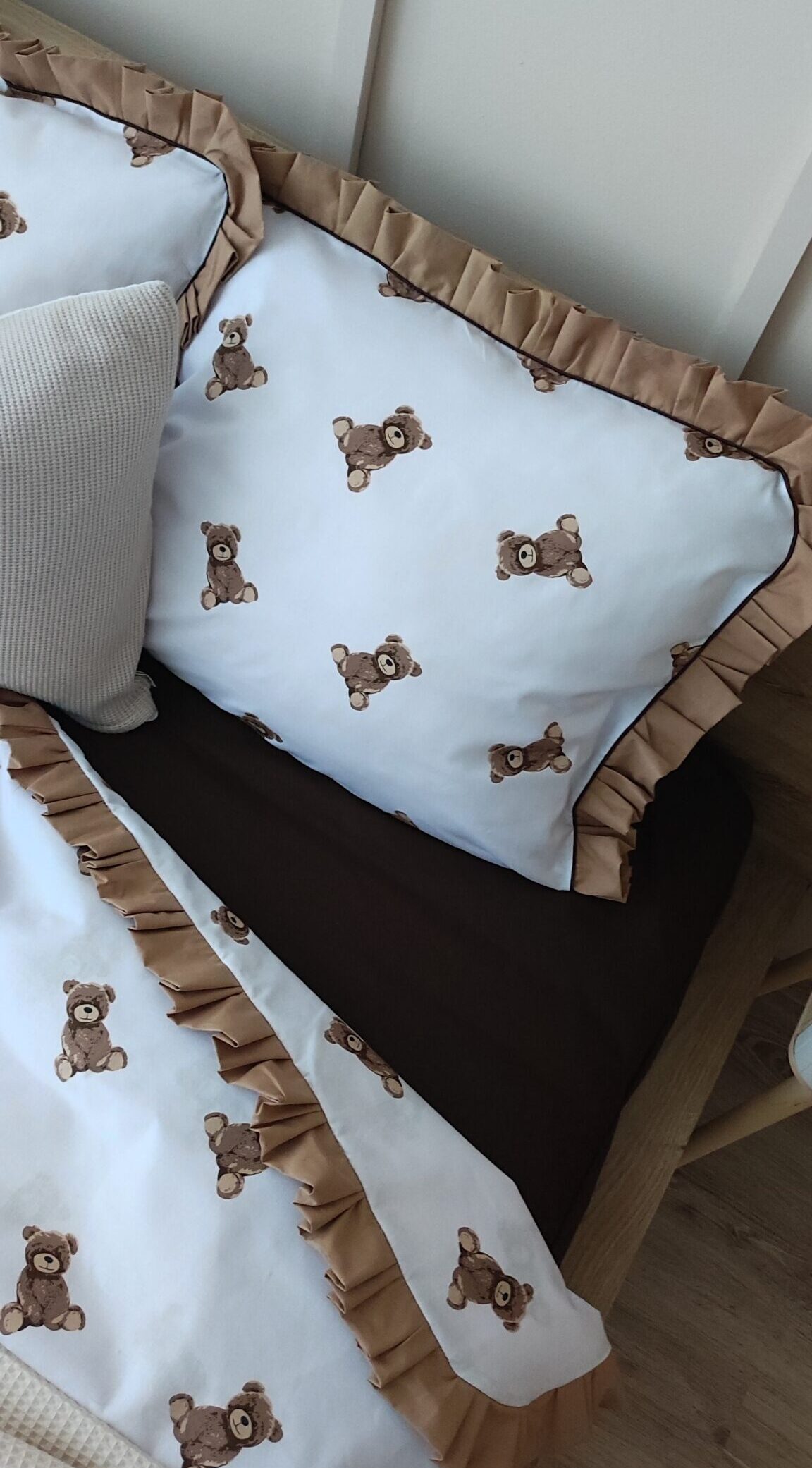 Dziecięcy komplet pościeli w brązowe misie na białym tle z karmelową falbanką i czekoladową wypustką.