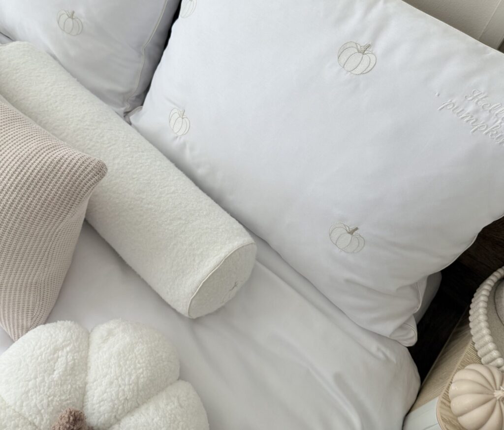 Poduszka wałek boucle z haftem dyni i wypustką w sypialni