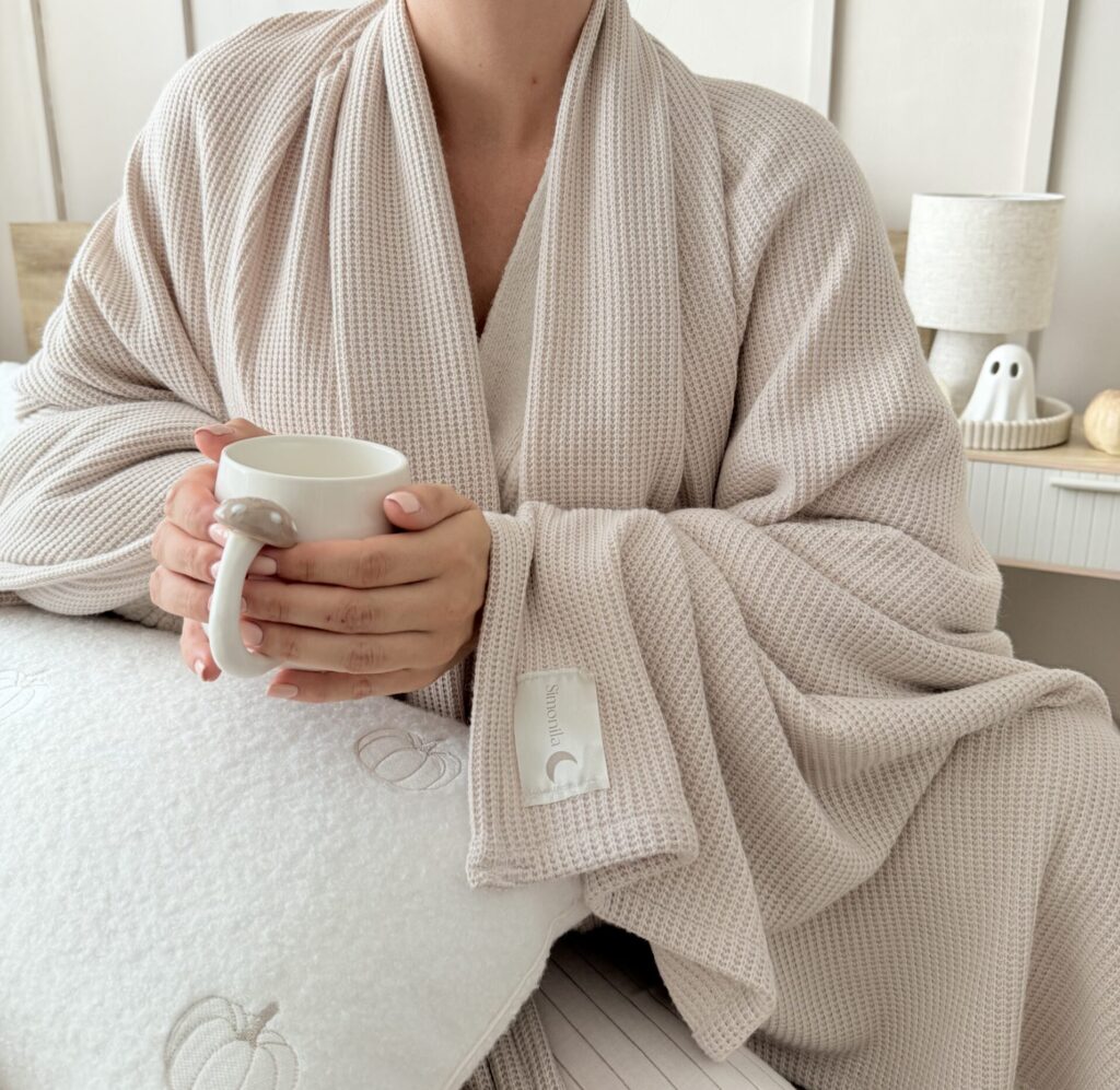 Zbliżenie na dzianinowy kocyk w jasnym beżu, pokazując miękką fakturę tkaniny premium, wytrzymały splot i przyjemny w dotyku materiał