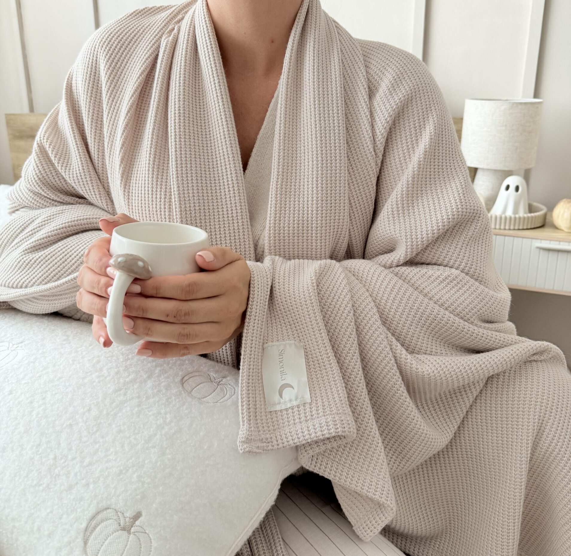 Zbliżenie na dzianinowy kocyk w jasnym beżu, pokazując miękką fakturę tkaniny premium, wytrzymały splot i przyjemny w dotyku materiał