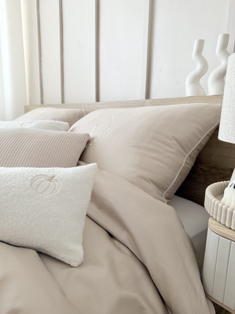 Komplet pościeli personalizowanej na łóżku - chłodny beż z haftem i atłasową wypustką Simonila