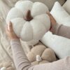 Ręcznie robiona poduszka dynia z miękkiego materiału boucle, z wypełnieniem, trzymana w dłoniach - produkt Simonila z jesiennej kolekcji