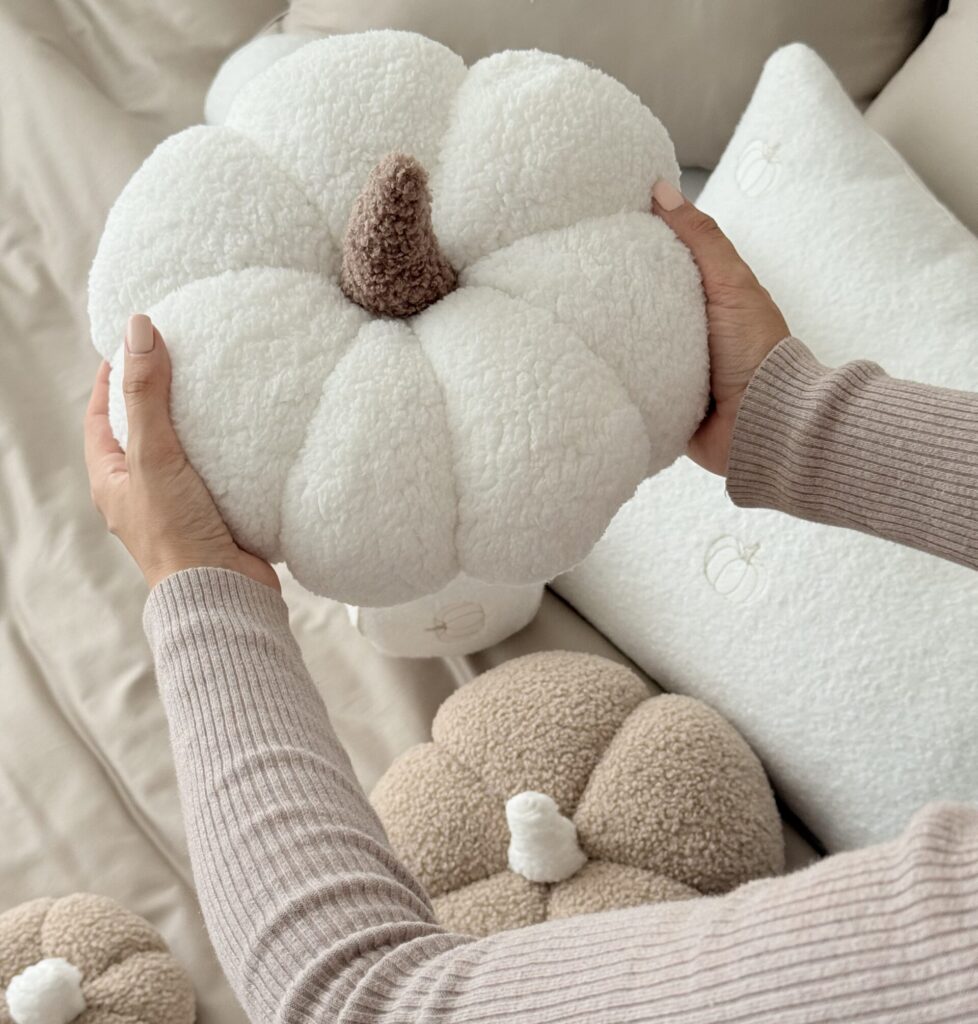 Ręcznie robiona poduszka dynia z miękkiego materiału boucle, z wypełnieniem, trzymana w dłoniach - produkt Simonila z jesiennej kolekcji