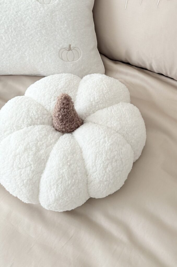 Ręcznie robiona poduszka dynia z miękkiego materiału boucle, z wypełnieniem, trzymana w dłoniach - produkt Simonila z jesiennej kolekcji