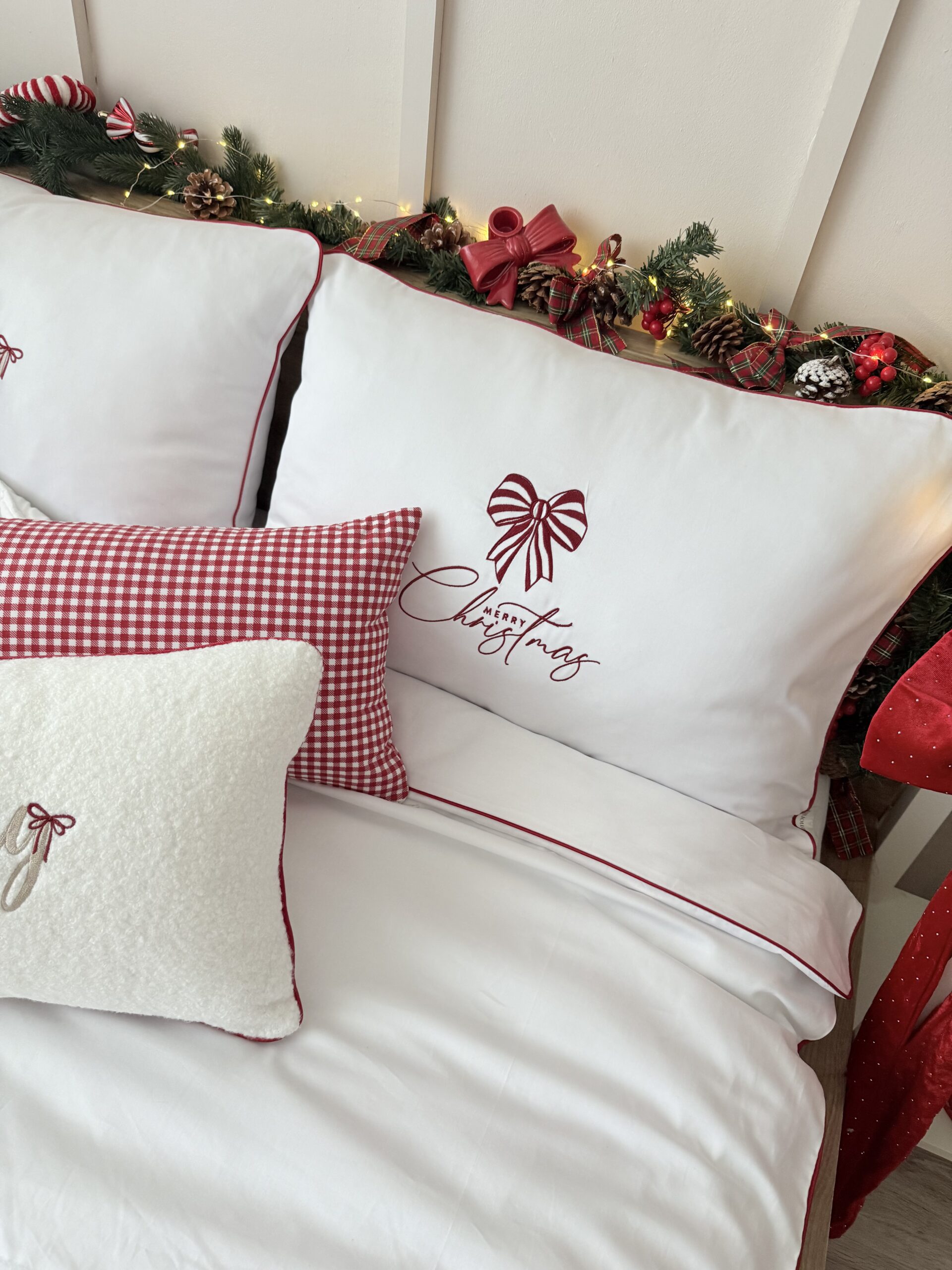 Detal haftu kokardy na białej pościeli świątecznej