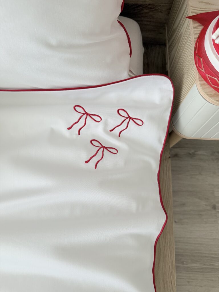 Świąteczna pościel z ramką i kokardą – detal atlasowej czerwonej wypustki
