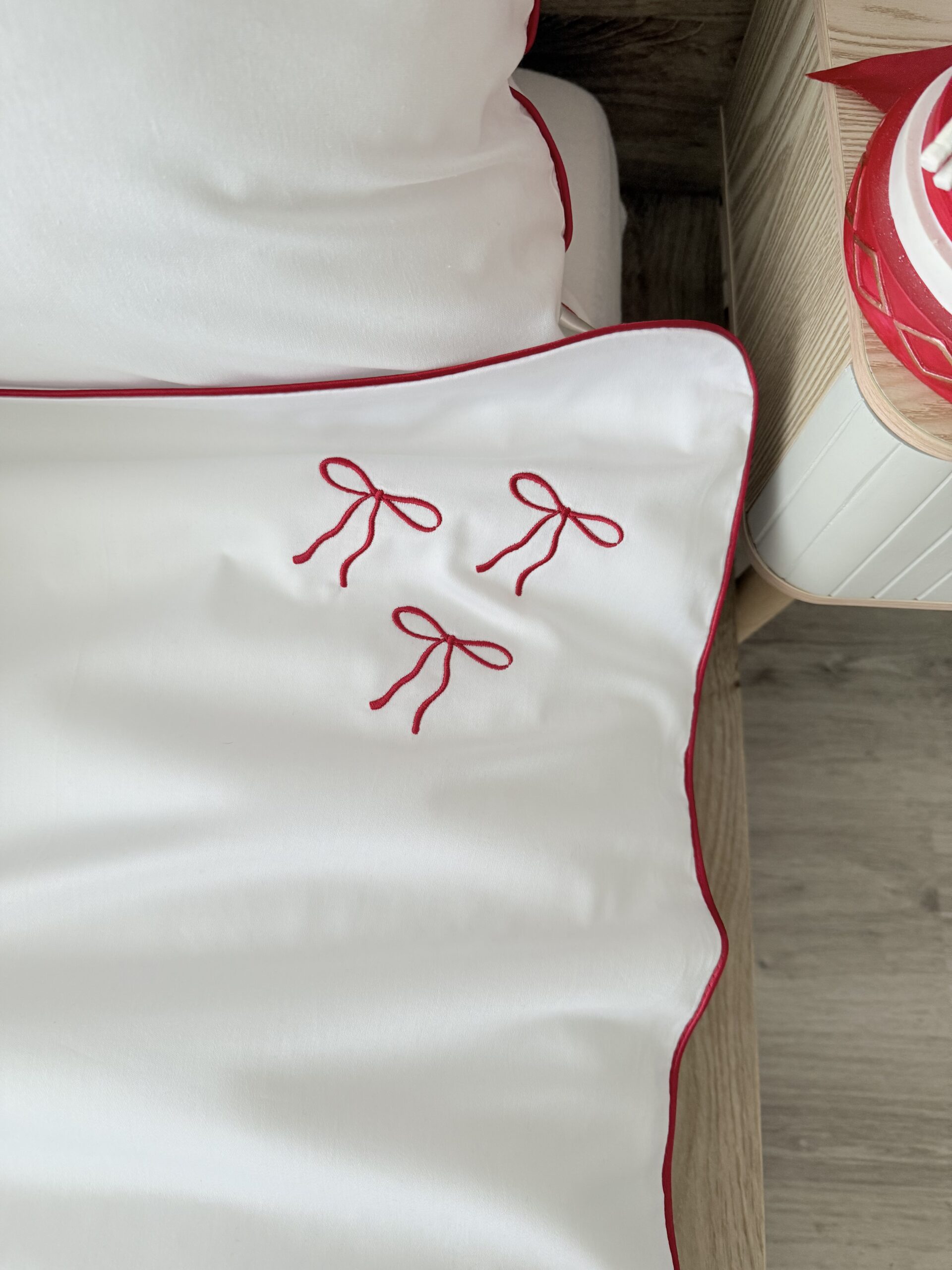 Świąteczna pościel z ramką i kokardą – detal atlasowej czerwonej wypustki